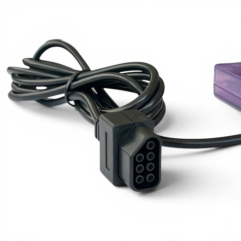 Op de afbeelding: Zwarte videospelcontrollerkabel met een rechthoekige connector met acht ronde pinholes. De kabel is opgerold en verbonden met een paarse rechthoekige component. De achtergrond is wit.
