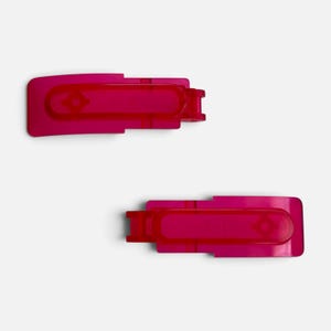 May include: Two rectangular hair clips in a vibrant translucent fuchsia pink color. Each clip features a smooth, flat surface with a central elongated oval indentation and a small diamond-shaped cutout detail at one end of the main body.