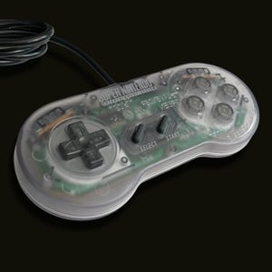 May include: A transparent Super Nintendo Entertainment System game controller with a black cord. The controller features a black directional pad, four clear action buttons, and black Select and Start buttons. The internal green circuit board is visible.
