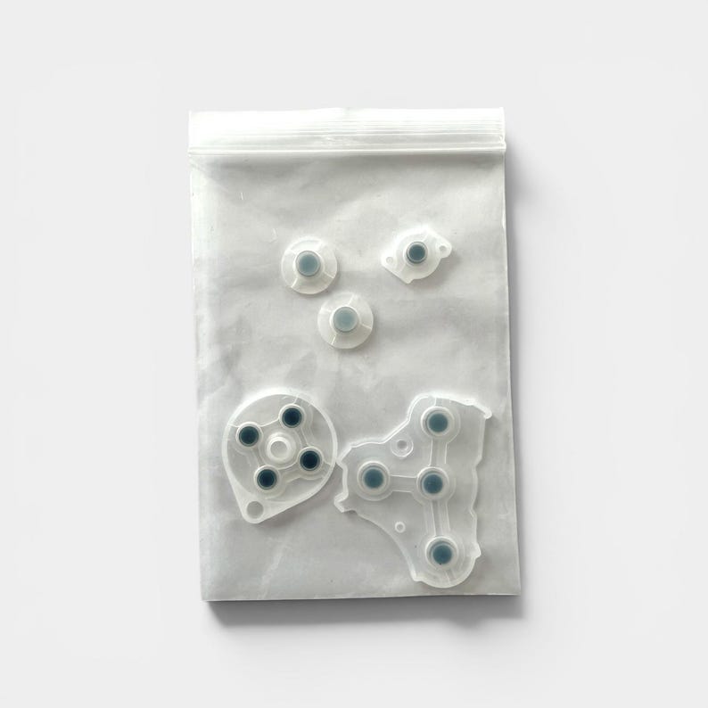Puede incluir: Una bolsa de pl&aacute;stico transparente que contiene varios reemplazos de botones de mando de juego blancos y grises. Los botones son de varias formas y tama&ntilde;os, incluidos dise&ntilde;os circulares y de almohadilla direccional. La bolsa est&aacute; sellada con un cierre de cremallera.