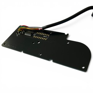 Op de afbeelding: Een zwarte printplaat met diverse elektronische componenten, waaronder pinnen en een chip. Meerkleurige draden en een zwarte kabel zijn bevestigd. De tekst "HELPER" is op de printplaat gedrukt.