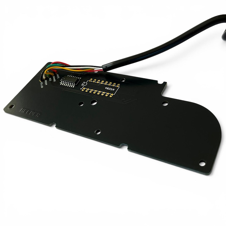 Op de afbeelding: Een zwarte printplaat met diverse elektronische componenten, waaronder pinnen en een chip. Meerkleurige draden en een zwarte kabel zijn bevestigd. De tekst "HELPER" is op de printplaat gedrukt.