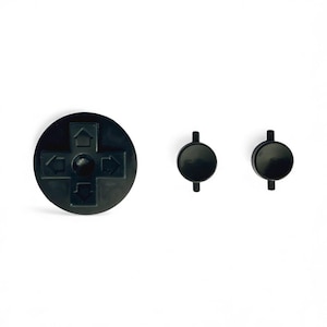May include: Black plastic video game controller buttons. The set includes a directional pad with arrows and two round buttons with small stems. The buttons are on a white background.
