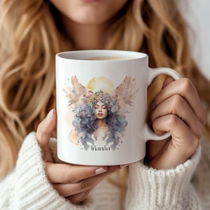 May include: White ceramic mug featuring a watercolor illustration of a woman with flowing blue hair, a floral crown, and angel wings. The mug has the name "Inanna" printed below the illustration. The design includes soft pastel colors and a golden sun.