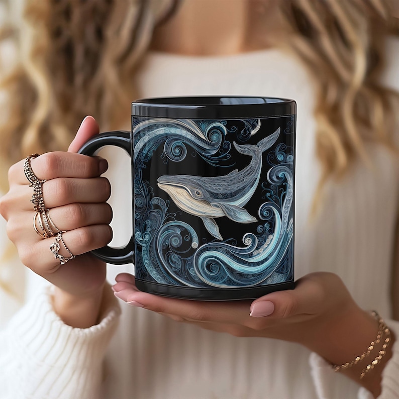 May include: Black ceramic mug featuring a detailed illustration of a whale swimming in stylized blue waves. The whale is depicted in shades of gray and white against a black background. The mug has a black handle.