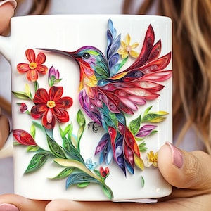 May include: A white ceramic mug with a colorful paper quilling hummingbird and flowers design. The hummingbird is red, blue, green, and yellow. The flowers are red and yellow.
