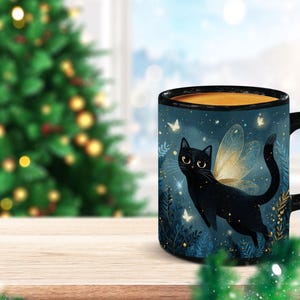 May include: A black cat with fairy wings is featured on a ceramic mug. The mug has a black handle and rim, and the background is a dark blue with white butterflies. The mug is on a wooden surface.