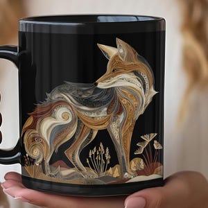 Puede incluir: Taza de cerámica negra con una ilustración detallada de un zorro. El zorro está representado en tonos marrones, beige y grises, con patrones intrincados. La taza tiene un asa y un interior negros. El diseño incluye plantas estilizadas.