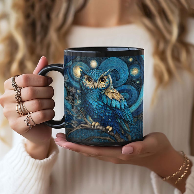 May include: A black ceramic mug featuring a detailed illustration of a blue owl perched on a branch against a swirling dark blue background with glowing yellow stars. The owl has large yellow eyes and textured blue and gold feathers.