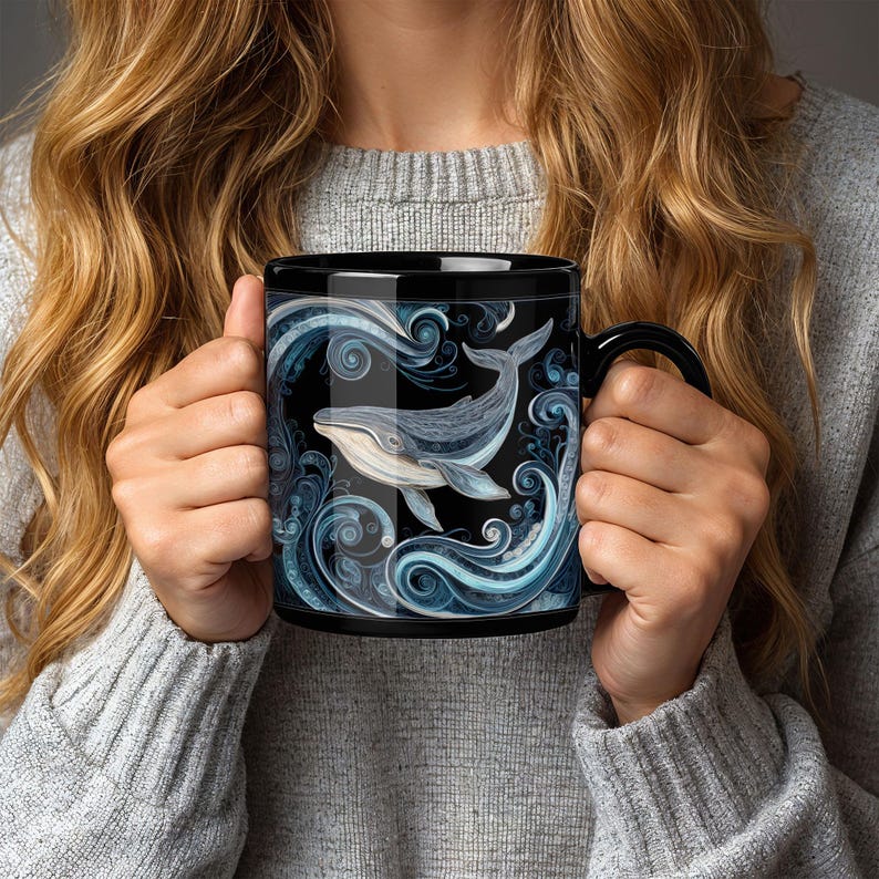 May include: Black ceramic mug featuring a detailed illustration of a whale swimming in stylized blue waves. The whale is depicted in shades of gray and blue, set against a black background. The mug has a black handle.