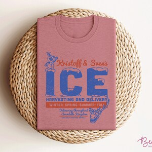 K&ouml;nnte beinhalten: Ein pinkfarbenes T-Shirt mit einem Vintage-Grafikdesign, das Olaf aus Frozen zeigt. Das Design lautet "Kristoff & Sven's ICE HARVESTING AND DELIVERY WINTER SPRING SUMMER FALL Delivering throughout Arendelle Kingdom CONTACT EVEN FOR DETAILS".