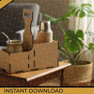 Op de afbeelding: Een houten caddy met compartimenten met een metalen thermoskan, een kleine beker met een rietje en een handvat. De caddy staat op een houten tafel. Het woord "DIGITAL" staat in een gouden banner. "DIRECT DOWNLOADEN".