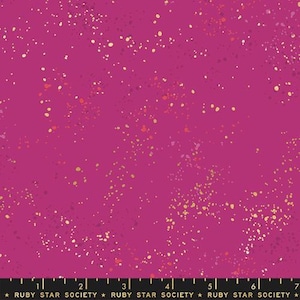 May include: A magenta fabric with a speckled pattern of gold, orange, and pink dots. The fabric has a smooth texture and is suitable for various sewing projects. The text "RUBY STAR SOCIETY" is printed at the bottom.