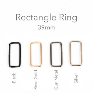 Può includere: Quattro anelli rettangolari neri, oro rosa, canna di fucile e argento. Gli anelli misurano 3,9 cm e sono esposti su sfondo bianco. Il testo "Rectangle Ring" è sopra gli anelli.