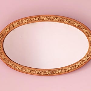 Oval wall mirror with gold and ornate frame
