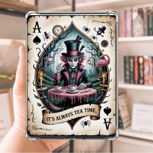 Peut inclure: Coque de tablette transparente avec un motif de carte à jouer. L'As de Pique représente le Chapelier Fou d'Alice au pays des merveilles, une table, des tasses à thé et un flamant rose. Le texte sur la bannière dit "IT'S ALWAYS TEA TIME."
