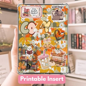 May include: A clear tablet case with a colorful autumn-themed design. The design includes fall leaves, pumpkins, books, and the words "Cozy Vibes" and "Printable Insert". The case has a plaid background and various stickers.