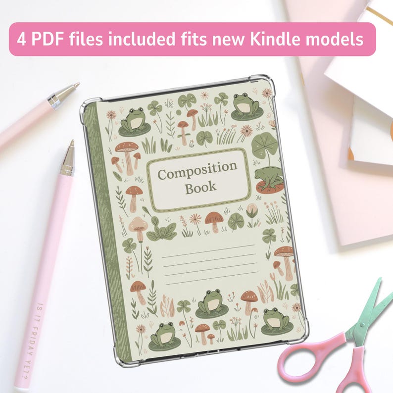 May include: A clear Kindle cover with a whimsical design featuring frogs, mushrooms, and foliage. The cover has the words "Composition Book" on the front. Two pink pens and a pair of pink scissors are also in the image.