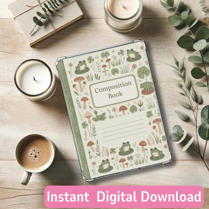 May include: A composition book with a whimsical design featuring frogs, mushrooms, and floral elements. The cover has the words "Composition Book" in a rectangular frame. The image also includes candles, a cup of coffee, and greenery.