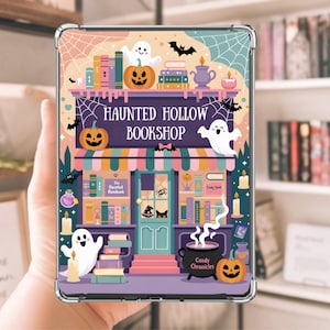 May include: A clear protective case featuring a colorful illustration of a Halloween-themed bookstore. The design includes pumpkins, ghosts, bats, and the text "Haunted Hollow Bookshop". The case is designed to fit a tablet or e-reader.