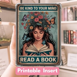 以下が含まれることがあります： 本を読む女性が描かれた装飾用の印刷可能なインサート。花と蝶が飾られています。「BE KIND TO YOUR MIND」と「READ A BOOK」というテキストがあります。インサートは、「Printable Insert」と書かれたピンク色のラベルが付いた透明なケースに入っています。