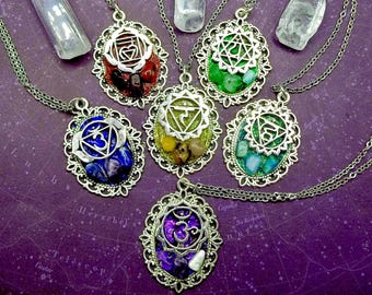 May include: Seven silver necklaces with ornate pendants featuring different colored gemstones and chakra symbols. Each pendant is surrounded by a decorative silver frame.