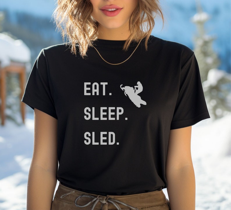 Puede incluir: Camiseta negra con texto blanco que dice "Comer. Dormir. Trineo." y una silueta de una persona conduciendo una moto de nieve.
