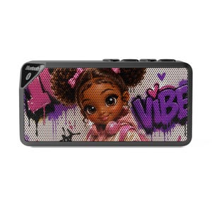 May include: A rectangular Bluetooth speaker with a black frame and a front grille featuring a graphic illustration of a young person with dark curly hair and pink bows. The design includes purple graffiti-style text reading VIBE and pink hearts.
