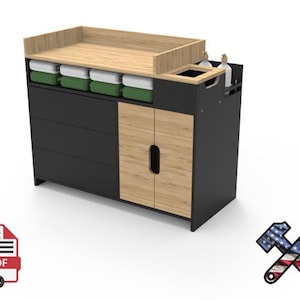 May include: A modern black and wood-tone changing table with drawers, cabinet doors, and a top surface. The table has a built-in compartment for supplies and a changing pad area. Includes green and white storage bins.