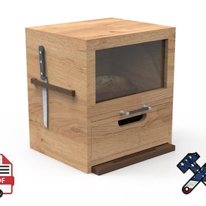 Puede incluir: Una panera de madera con ventana de cristal, cajón y soporte para cuchillo. Un cuchillo de pan está sujeto al lateral. La panera es de madera marrón claro. El cajón tiene un asa. Se ve una hogaza de pan dentro.