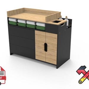 Op de afbeelding: Een moderne commode in zwart en houttinten met een licht houten blad en kastdeuren. Het heeft drie lades, open opbergruimte en een ingebouwd compartiment. Inclusief groene en witte opbergbakken.