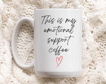 May include: White ceramic coffee mug with black text that reads "This is my emotional support coffee" and a red heart.