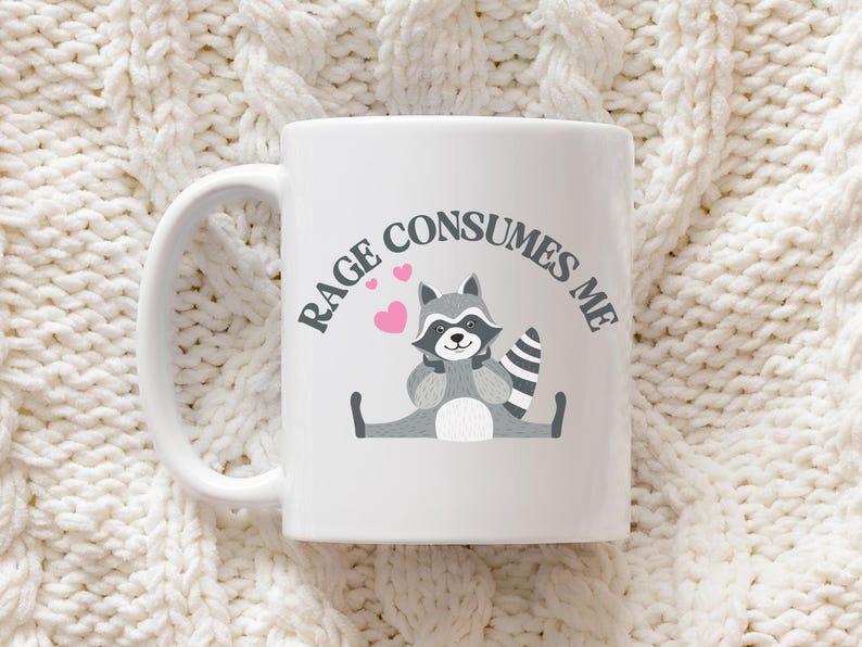 Peut inclure: Une tasse en c&eacute;ramique blanche avec une illustration de raton laveur noir et gris et le texte "Rage Consumes Me".