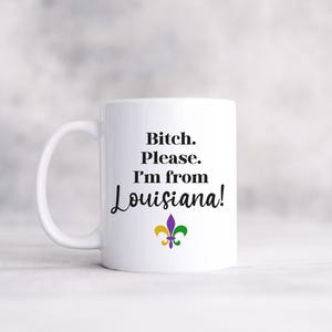 May include: White ceramic mug with the text "Bitch. Please. I'm from Louisiana!" in black script. A fleur-de-lis in purple, green, and gold is below the text. The mug has a white handle.