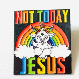 May include: A black enamel pin with a rainbow background and a white goat with horns and a pentagram on its forehead. The goat is sitting on a cloud and the text "NOT TODAY JESUS" is above it.