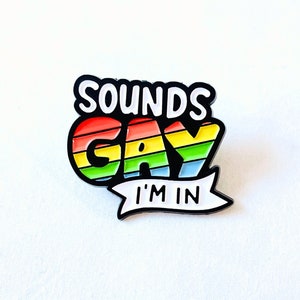 May include: A rainbow-colored enamel pin with the text "Sounds Gay I'm In" in white lettering.