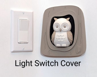 May include: A white light switch and a decorative light switch cover. The cover is shaped like a tree with a white owl inside. The text "Light Switch Cover" is below the light switch and cover.