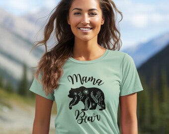 May include: A light green t-shirt with a black silhouette of a bear with floral details. The text "Mama Bear" is printed on the shirt.