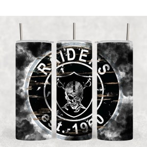 Könnte beinhalten: Ein schwarz-weißer Becher mit einem Raiders-Logo. Das Logo ist ein Schädel mit gekreuzten Schwertern und den Worten "Raiders Est. 1960". Der Hintergrund ist ein schwarz-weißes Wolkenmuster.