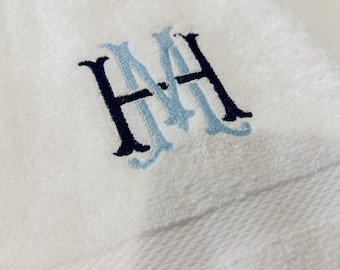 May include: White towel with a blue and black embroidered monogram "MH".