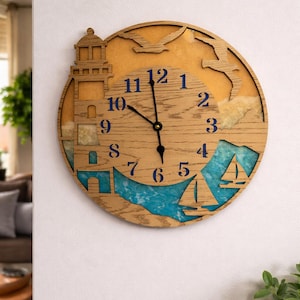 Puede incluir: Reloj de pared de madera con temática náutica. El reloj presenta un faro, veleros y gaviotas, con detalles en azul que representan el mar. Las manecillas del reloj son negras y los números azules.
