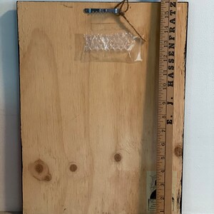 May include: The back of a wooden framed picture with a black frame. The frame is 18 inches tall. The back of the frame is made of plywood and has a clear plastic bubble wrap sticker on it.