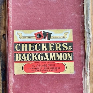 May include: A vintage red and gold "Checkers & Backgammon" game set. The box features the text "Gold Medal" and "De Luxe Edition". The label also reads "The Complete Outfit with Numbered Checkerboard and Booklet of Trick Moves".