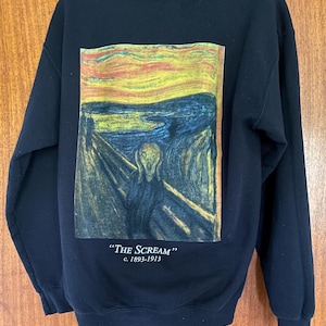May include: Black hoodie featuring a print of Edvard Munch's "The Scream" painting. The artwork depicts a figure with a distorted face against a swirling sky. The text "THE SCREAM" and the dates c. 1893-1913 are printed below the image.