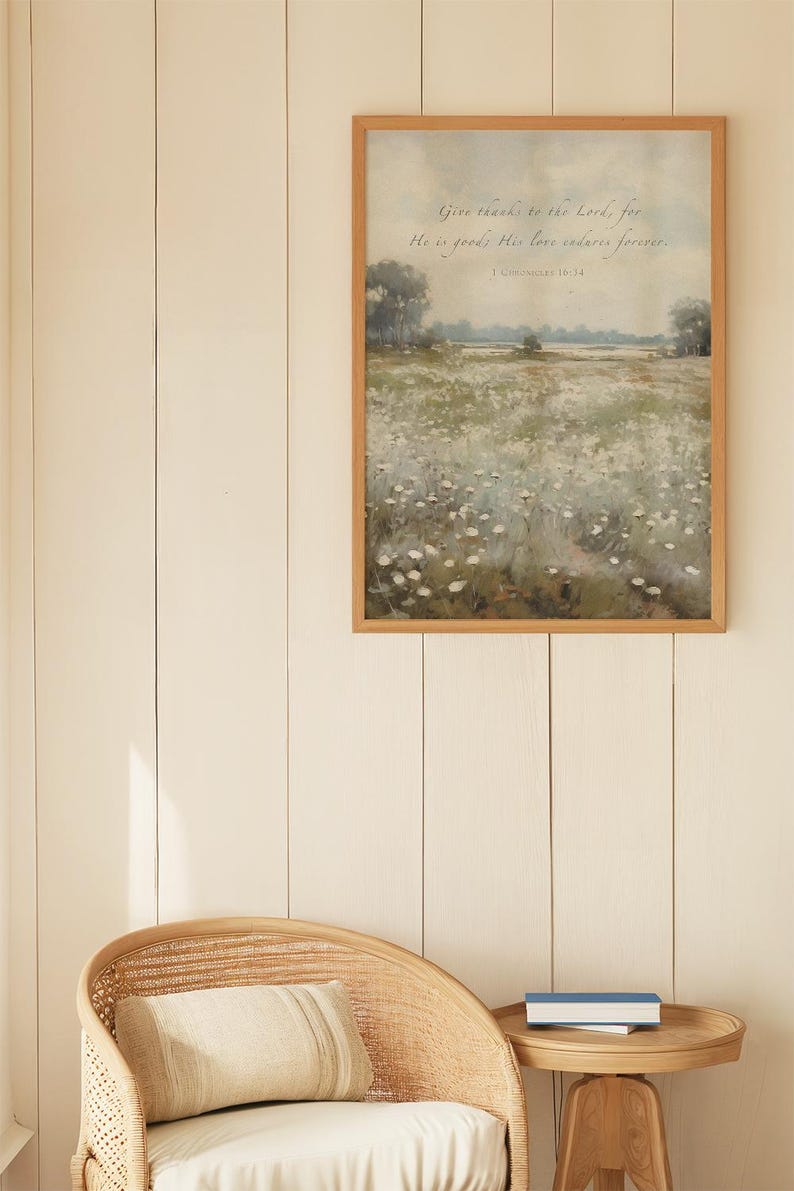 May include: A framed landscape art print with a wooden frame. The artwork depicts a field of white flowers under a soft, cloudy sky. The text "Give thanks to the Lord, for He is good; His love endures forever" is written at the top.