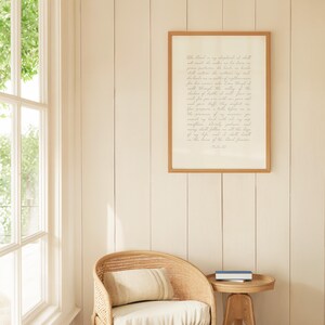 May include: A rectangular wall art print featuring the text of Psalm 23 in a cursive script, enclosed in a light brown wooden frame. The print has a cream-colored background with dark text, displayed on a vertical paneled wall above a chair.