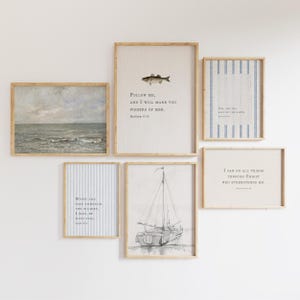 Può includere: Un set di sei stampe incorniciate da parete che include un dipinto di paesaggio marino, un'illustrazione di pesce con il testo Follow Me, And I Will Make You Fishers Of Men, una stampa a righe blu, uno schizzo di barca a vela e due testi.