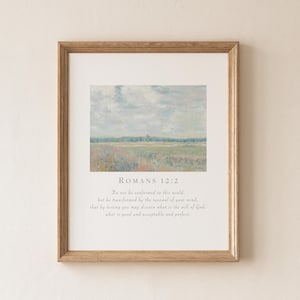 May include: A framed print with a landscape painting in a light brown wooden frame. The artwork has a soft, impressionistic style. The text "ROMANS 12:2" and a related passage are printed below the painting.