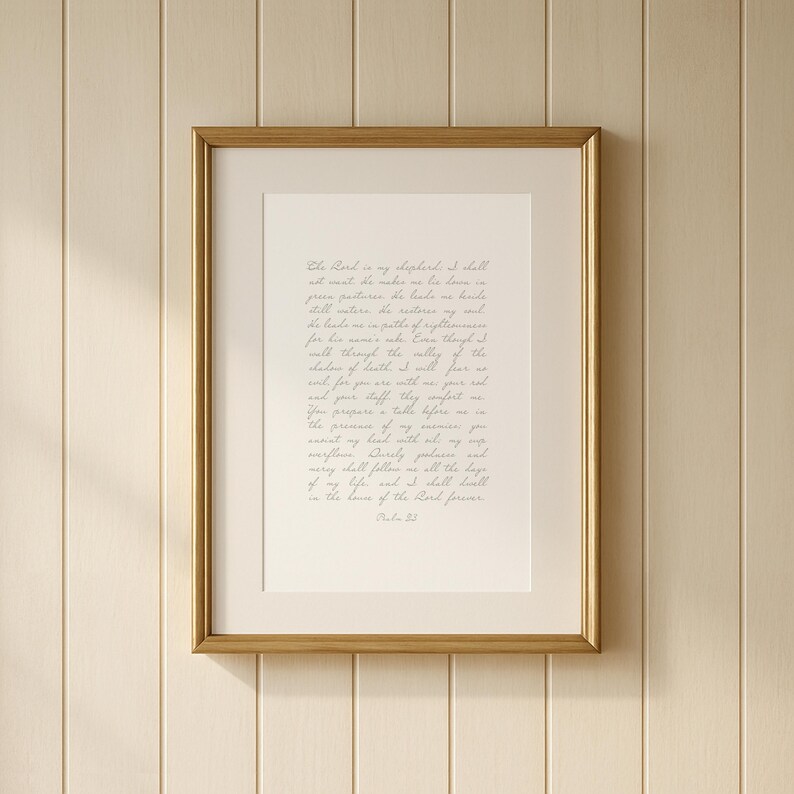 May include: A framed wall art piece featuring Psalm 23 written in elegant, light-colored cursive script on a cream-colored background. The text is enclosed within a thin, metallic gold frame, creating a clean and focused presentation of the scripture.
