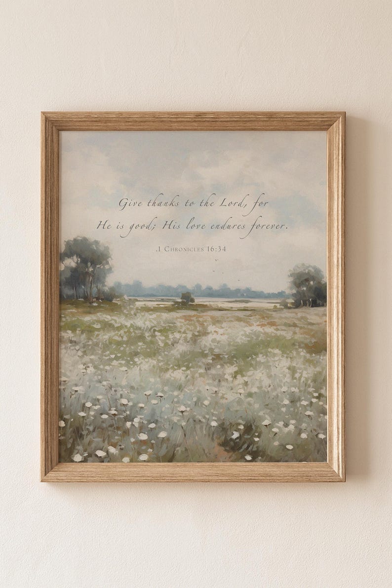 May include: A framed print featuring a pastoral landscape with a field of white flowers, trees, and a soft blue sky. The artwork includes the text "Give thanks to the Lord, for He is good; His love endures forever." from 1 Chronicles 16:34.